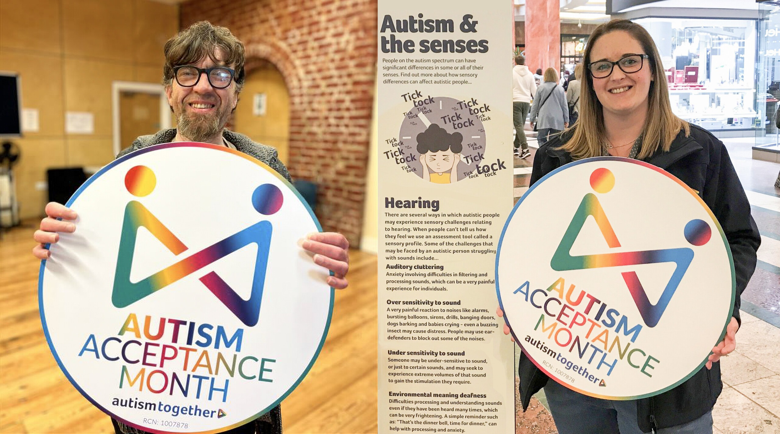 Grant (left), one of the people Autism Together supports is standing and holding an Autism Acceptance Month sign. To the right, Chloe Jones, Fundraising Officer at Autism Together, is also standing and holding the same sign. She is pictured next to a display about how autism can affect the senses, in this case - hearing.